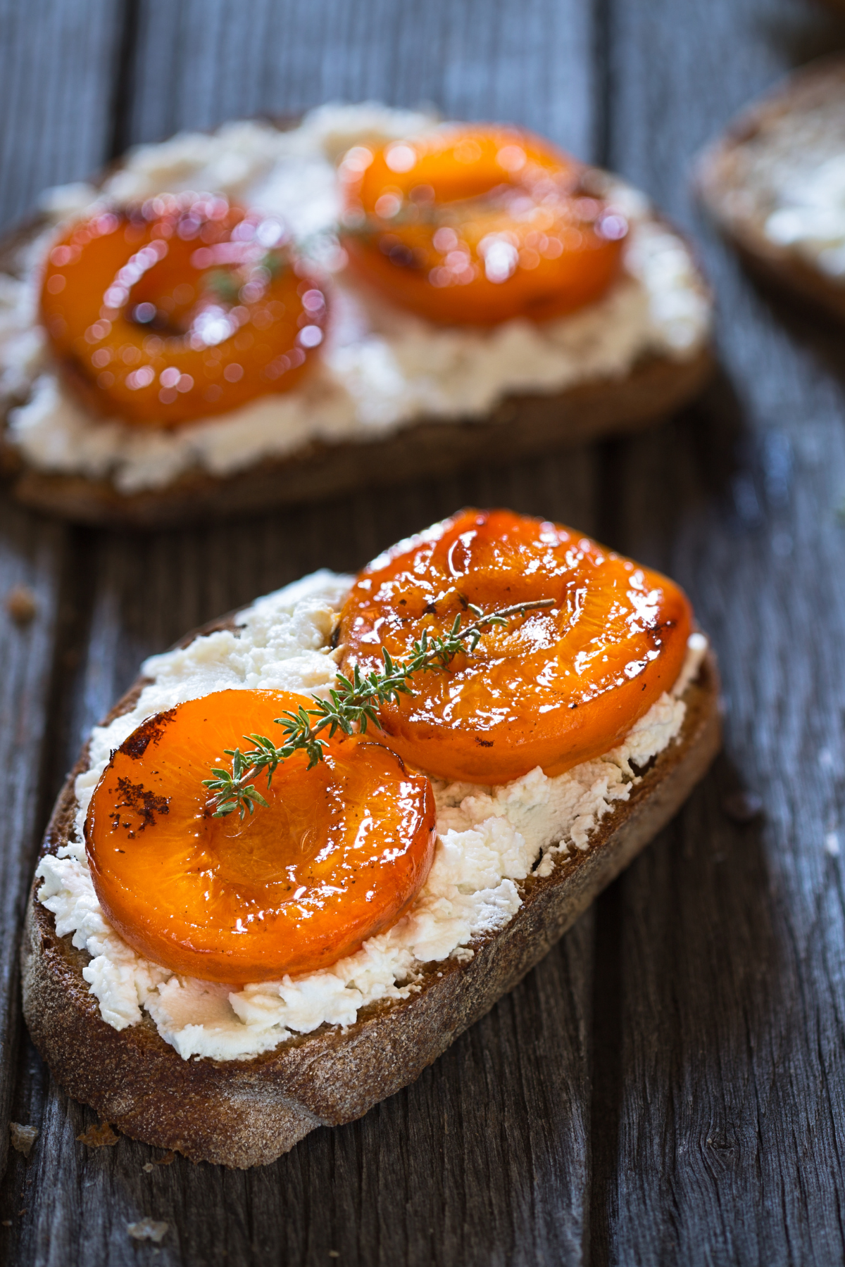 tomato goat cheese crostini on a white plate with cherry tomatoes and balsamic glaze on top